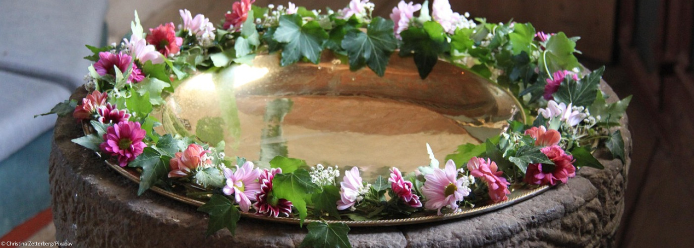 Taufstein mit Blumenkranz