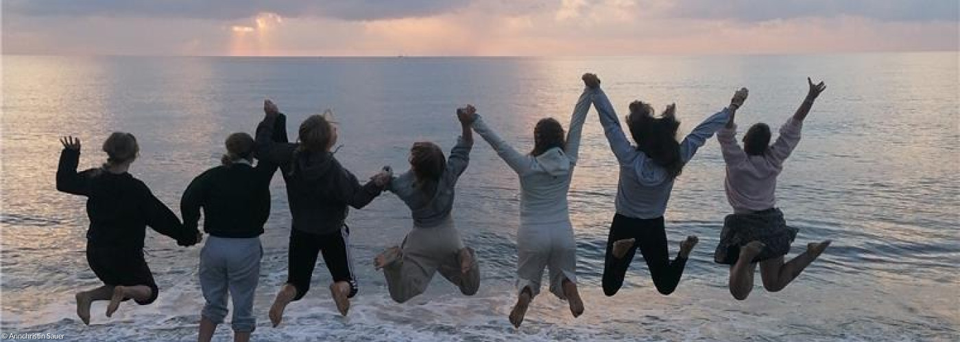 Jugendliche, die sich an den Händen halten und am Strand in die Luft springen