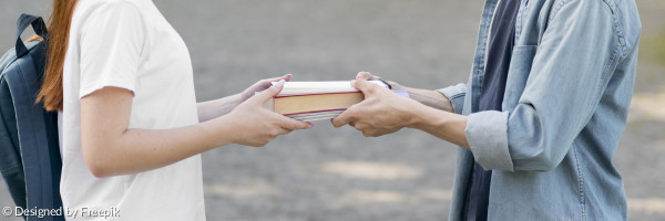 Zwei Menschen geben sich ein Buch in die Hand